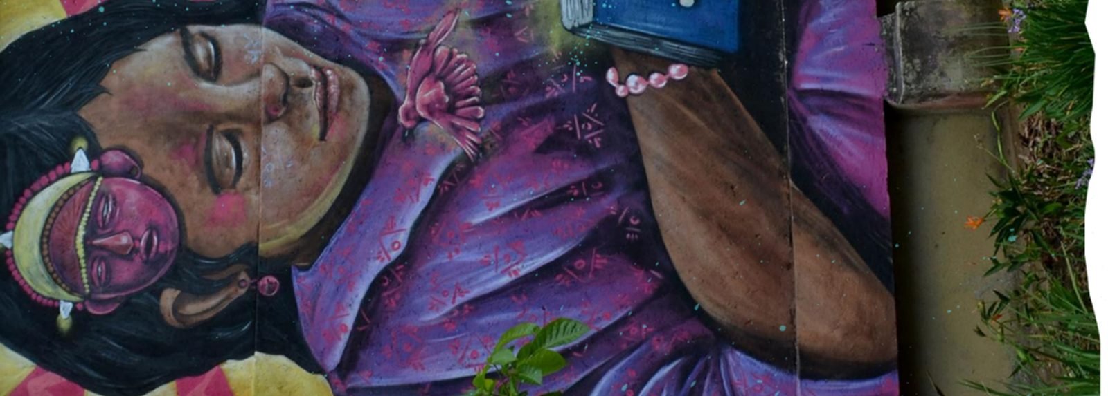 Mural de Territorio Libro: una mujer leyendo, pintada sobre una pared de la ciudad